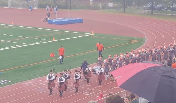 Macalester coach KiJuan Ware leads his team on to the field with school's bagpipe band