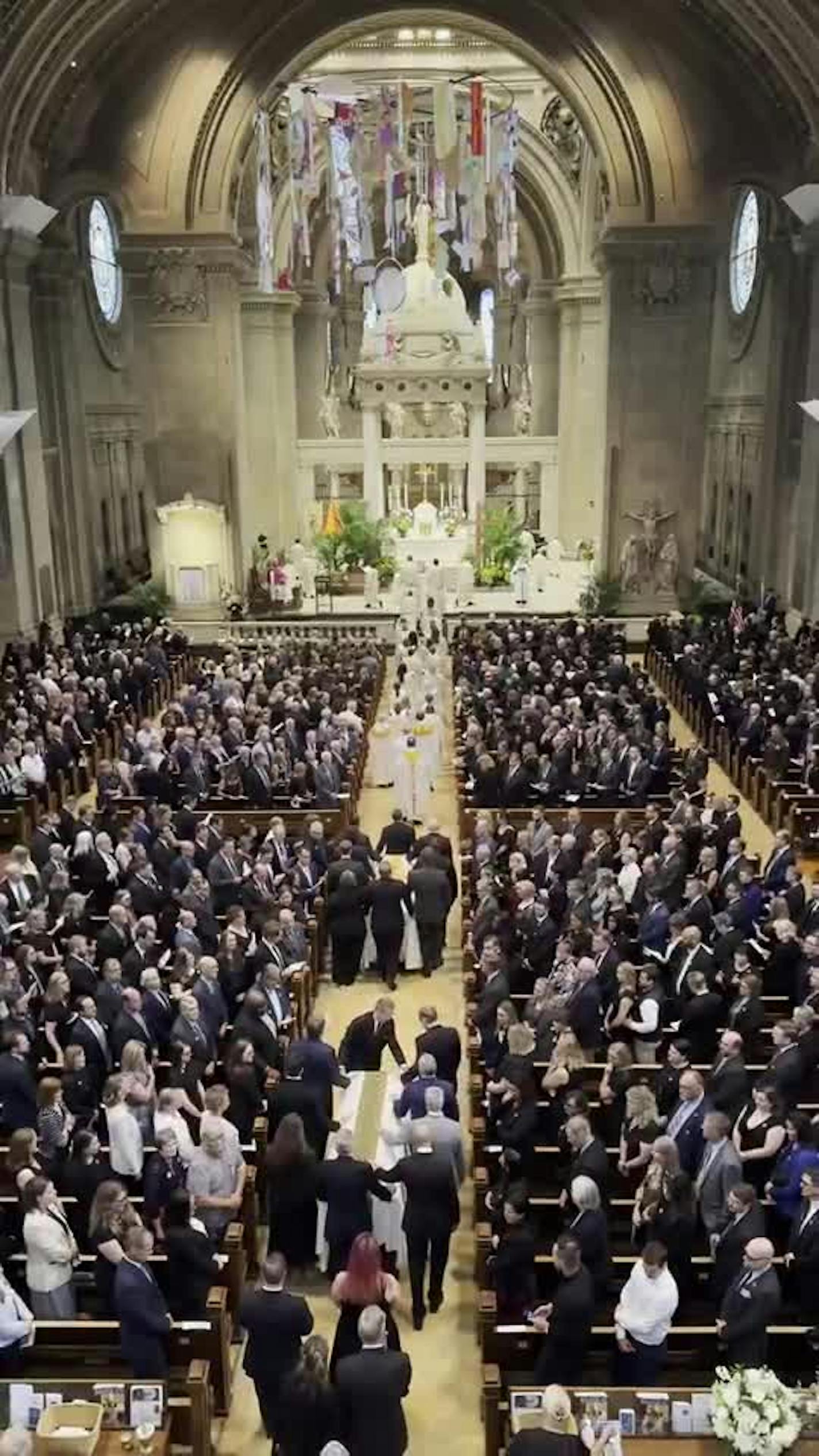 The caskets of the Hortmans are escorted to the front of the Basilica Saturday
