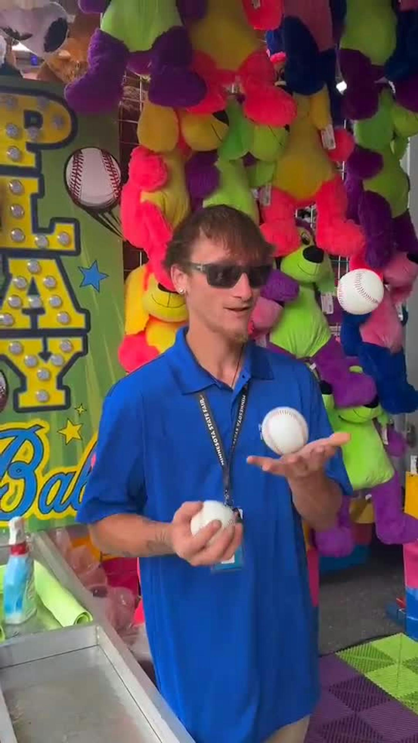 Nick Hacker juggles baseballs as he waits for players to step up to the game booth