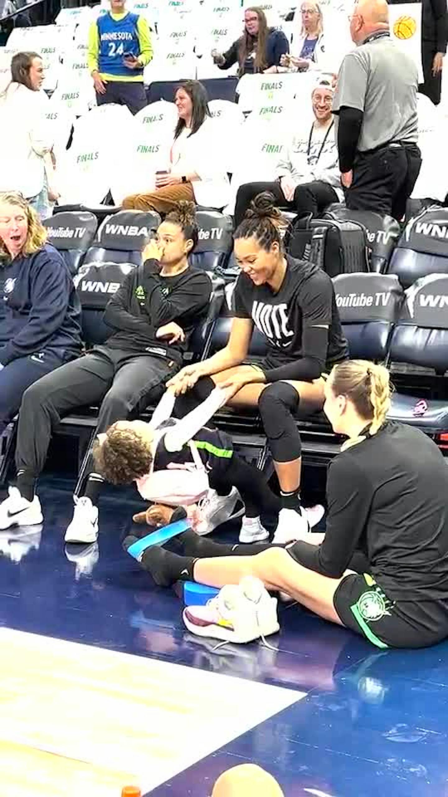 Napheesa Collier and her daughter sit court side at the Target Center